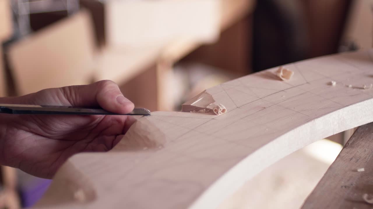 Tukang kayu mengukir detail dengan cermat ke dalam balok kayu besar melengkung menggunakan perkakas tangan tradisional. Tampilan gerak lambat close-up dari proses ukiran kayu.