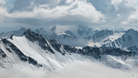 air flight through mountain clouds over beautiful snow-capped peaks of mountains and glaciers.