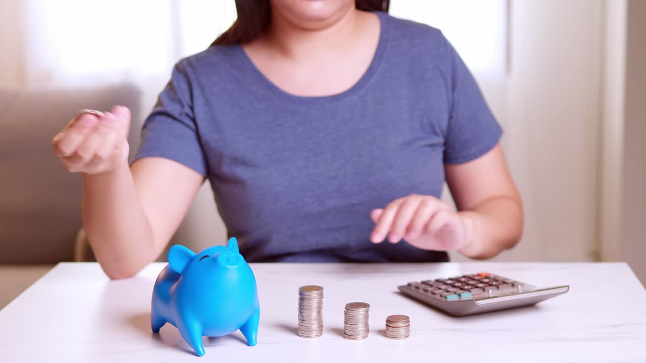 Donne usano calcolatrici e inseriscono monete in salvadanai blu, come metafore per separare i tipi di denaro per spese e risparmi.