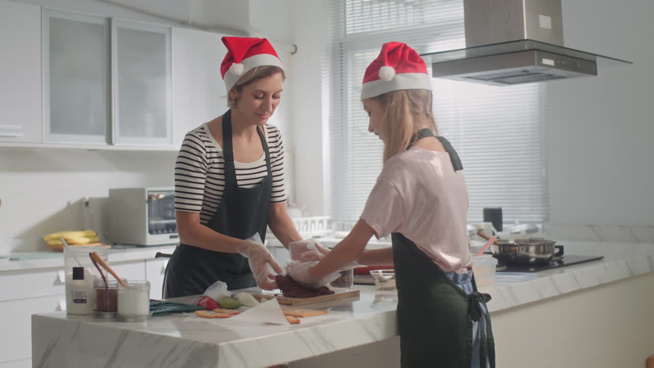 Daughter and Mom in Hats Kneading Dough for Christmas Cookies
