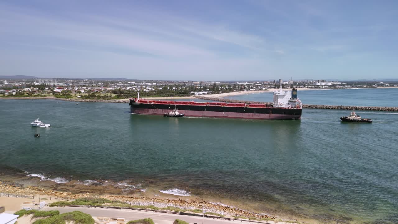 Pilot tug boats guide oil tanker into harbour at Newcastle, Australia