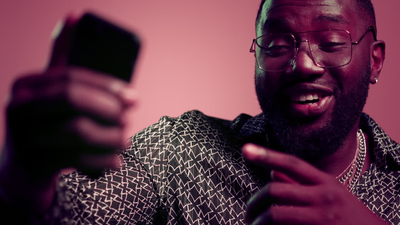 유쾌한 아프로 남자가 스튜디오에서 비디오 채팅하고 있습니다. 아프로 남자가 실내에서 스마트폰을 사용하고 있습니다.