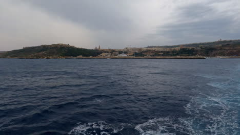 Slow-Motion-view,-looking-back-from-water-at-Valletta,-Malta