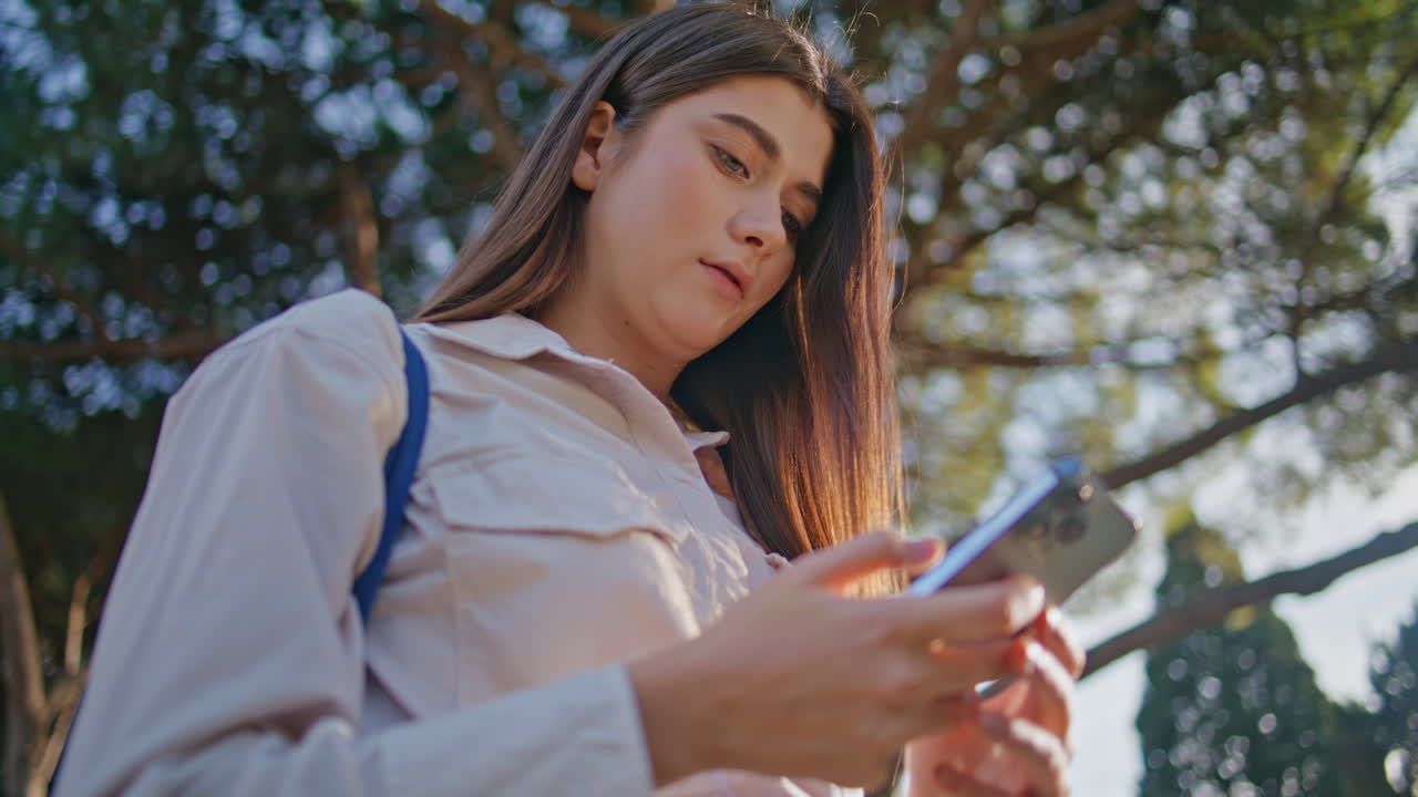 chica pensativa navegando por el teléfono inteligente en el parque soleado. mujer de primer plano mensajería