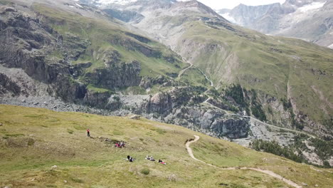 drone aerial view of a zermatt mountain valley with hiking path and grass, walkers and bikers playground for sport activities, nature landscape