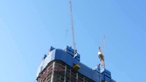 cranes on top of a skyscraper under construction