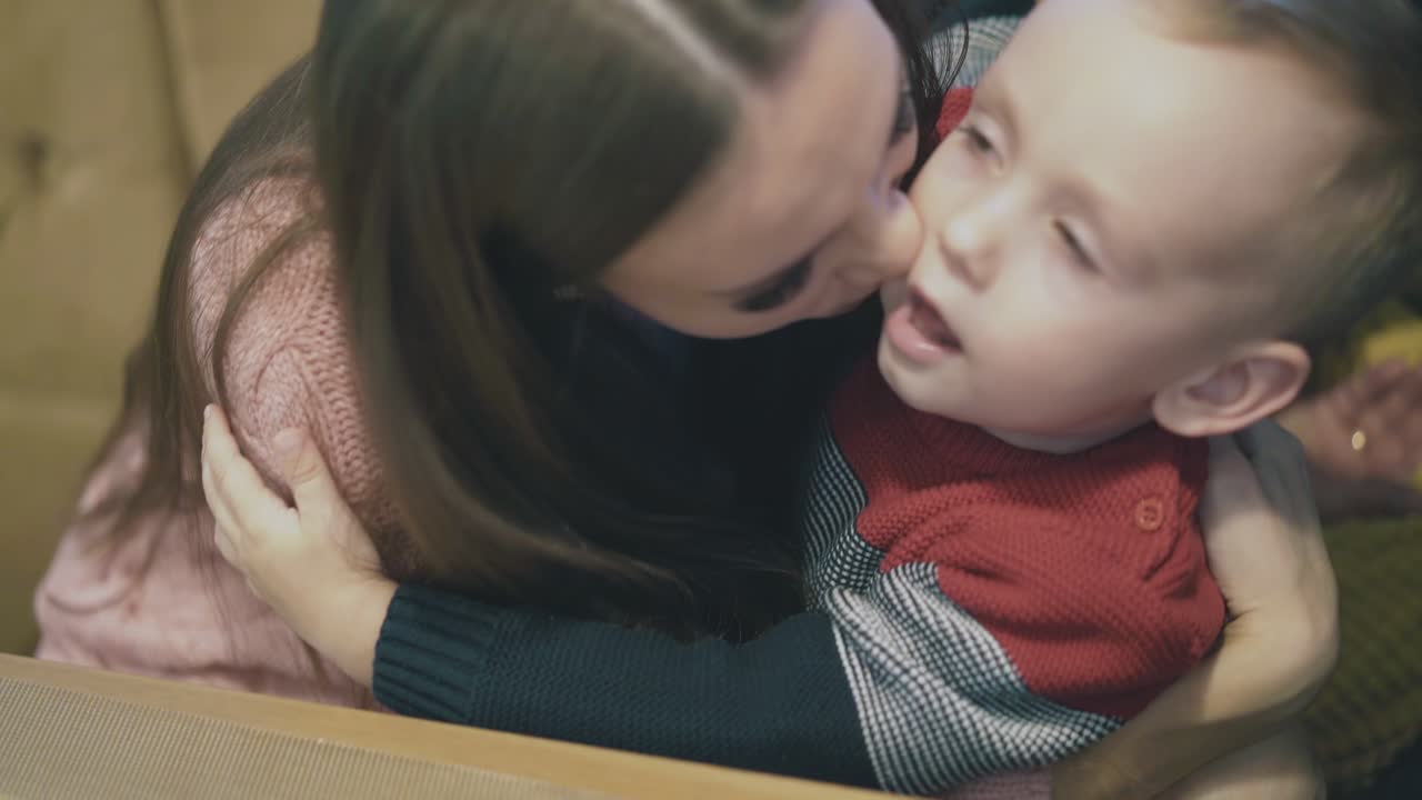 어린 소년 은 어머니 를 포옹 하고 갈색 소파 에 앉아 있는 혀 를 보여준다