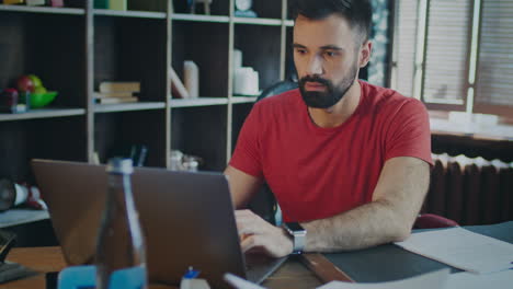 joven hombre de negocios elegante trabajando en una computadora portátil con expresión concentrada en la cara