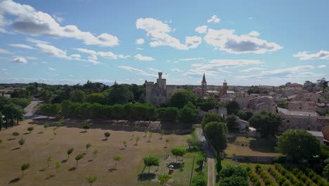 aerial establishing shot of chateau pouzihllac from over a field of vineyards