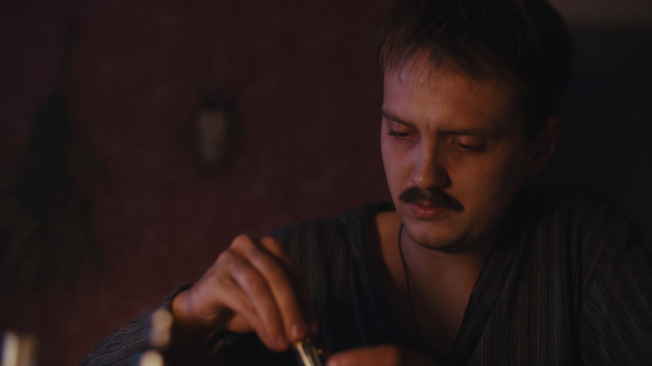 Man with a mustache gesturing in a dimly lit room