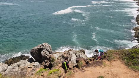 hikers on a cliffside path near the ocean