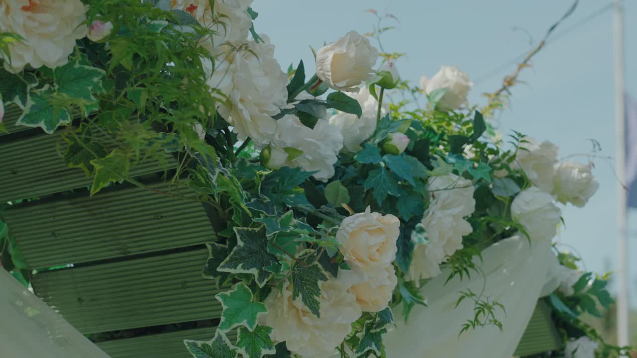 Closeup of white roses and green leaves wedding floral arch