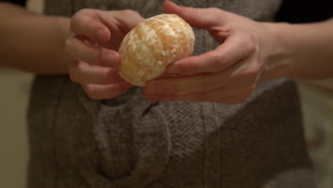 close shot, hands peeling an orange, mandarine