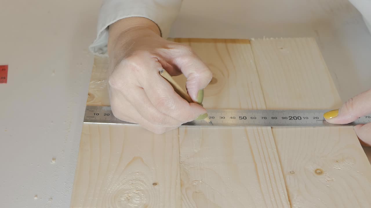 la niña constructora hace una marca de lápiz en un producto de madera para una acción posterior. obras de carpintería. 4k