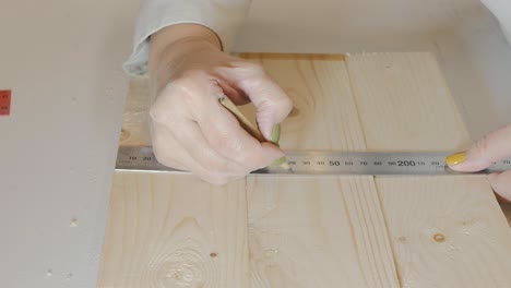 la niña constructora hace una marca de lápiz en un producto de madera para una acción posterior. obras de carpintería. 4k