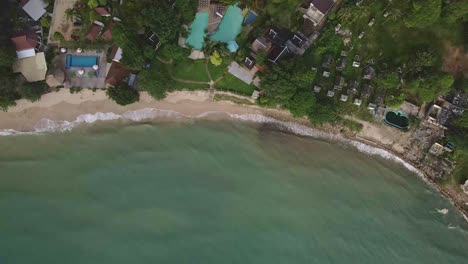 Vista-Aérea-De-Pájaros-De-Una-Playa-Con-Un-Complejo-Turístico-De-Bungalows-De-Playa-Abandonado-Junto-A-Otros-Pequeños-Hoteles-Y-Complejos-Turísticos-En-Koh-Chang-Tailandia-Debido-Al-Efecto-Del-Covid-En-Los-Viajes-Y-El-Turismo-Mundiales