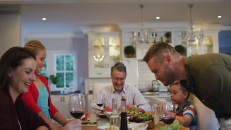 happy caucasian father giving speech and sitting down at table for family meal