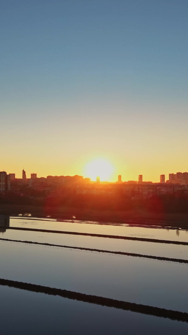 Sunrise over salt fields near urban area
