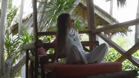 slim girl sitting on cushion of a wooden structure in the jungle