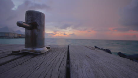 sun setting over sea with boat hook in foreground