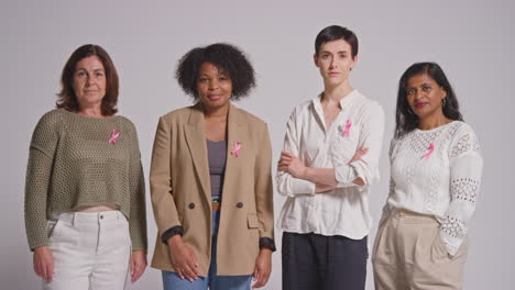 retrato de estudio de un grupo multirracial de mujeres de diferentes edades con expresiones serias que llevan cintas rosas de concienciación sobre el cáncer de mama contra un fondo blanco