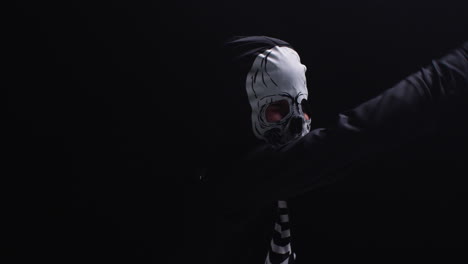 studio shot of child dressed up in skeleton costume trick or treating at halloween dancing against black background 1