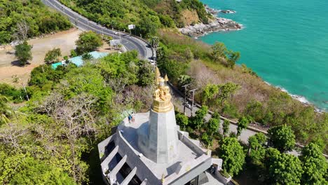 drone footage captures the scenic promthep cape lighthouse in phuket, thailand, showcasing lush greenery and turquoise waters under clear skies