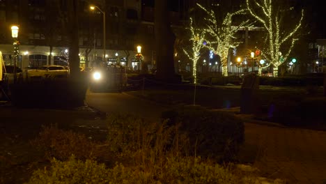 4k: a kids passenger-amusement train passes by in the park during the christmas time at night as parents watch nearby.