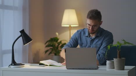 Un-Hombre-Adulto-Está-Recibiendo-Educación-En-Línea-Maestría-Desarrollo-Profesional-Autoeducación-Buscando-Información-En-Una-Computadora-Portátil-Y-Tomando-Notas