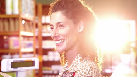 Female-staff-looking-at-a-grocery-item-at-payment-counter