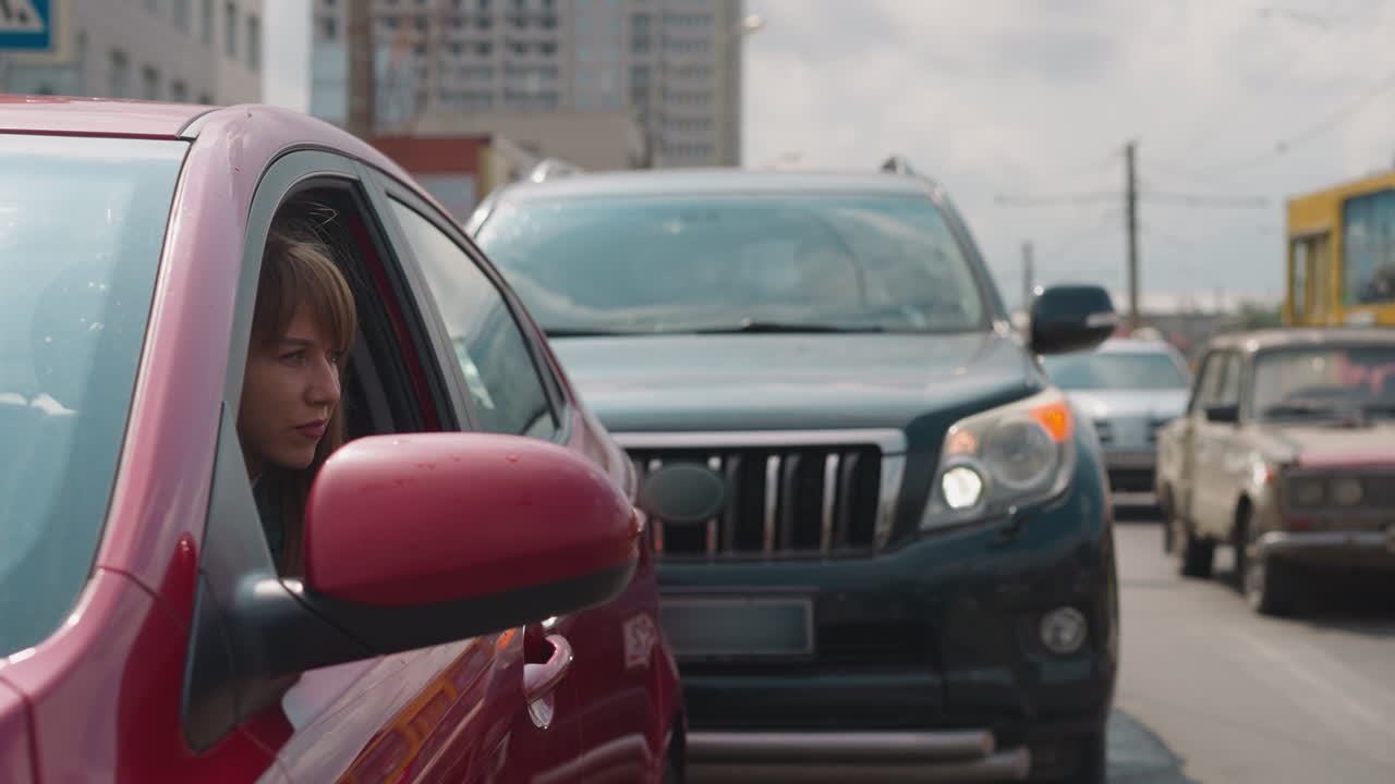 mujer curiosa mira por la ventana del coche rojo para examinar la carretera