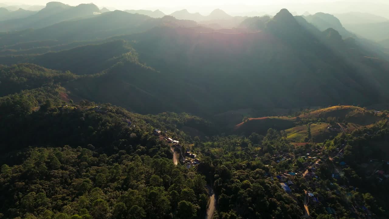Drone sobre a paisagem montanhosa da província de Mae Hong Son, no norte da Tailândia, ao pôr do sol. Filmagem aérea de uma pequena estrada isolada, famoso destino de viagem para motociclistas.