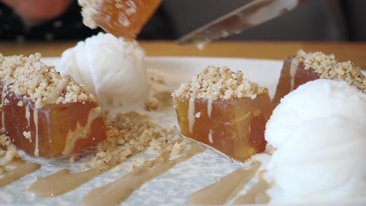 Tagliare e mangiare un dolce di zucca con gelato e noci