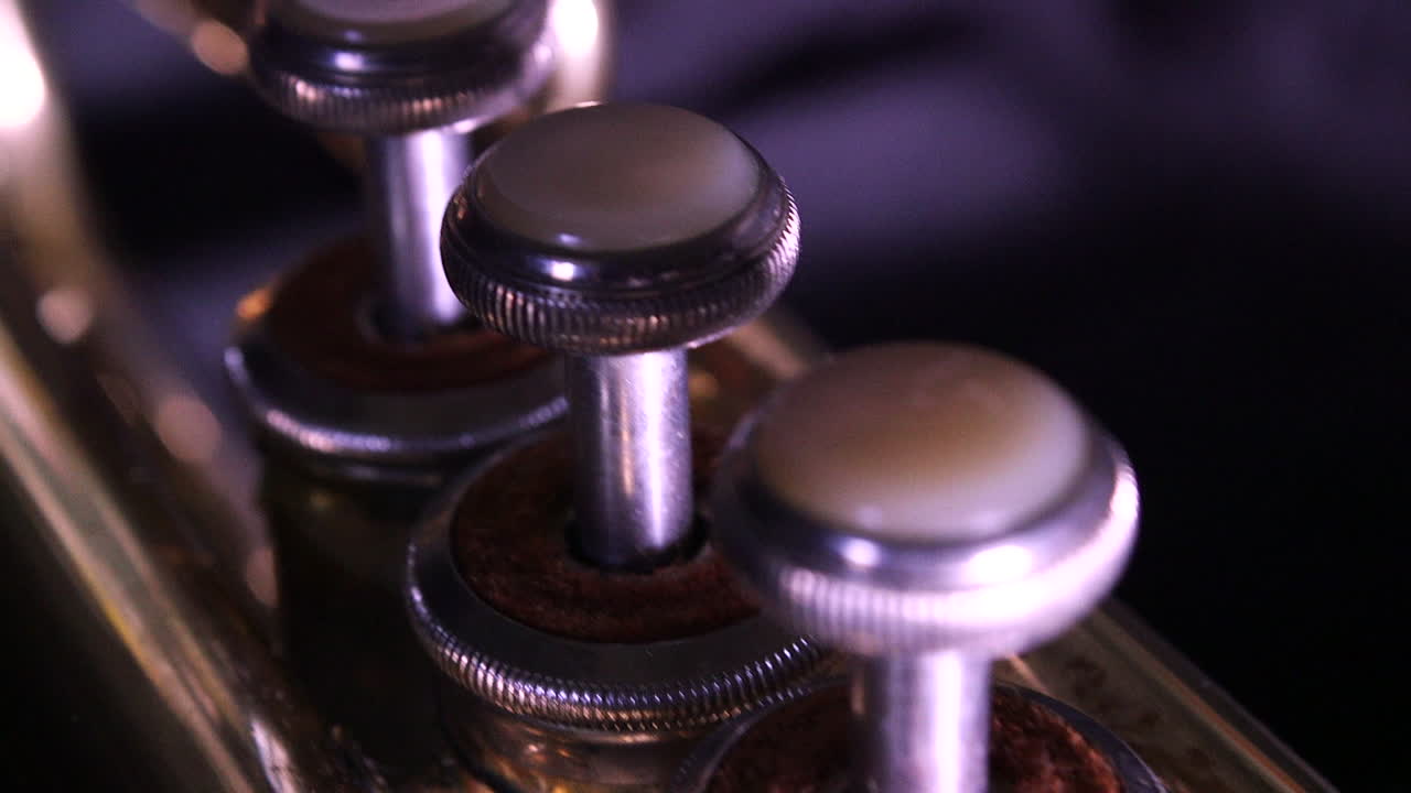 Dolly shot of the three valves on a brass trumpet.