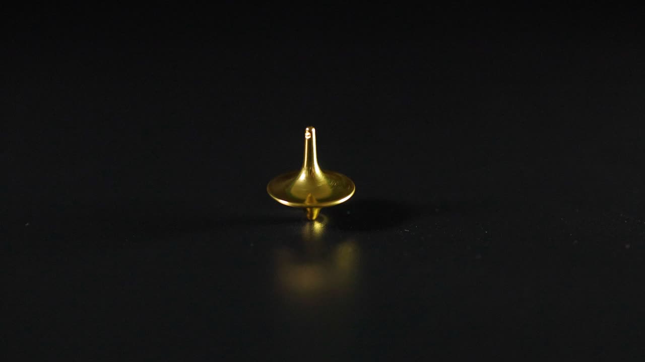 금색 꼭대기가 검은색 표면에서 회전하고 흔들리고 있습니다.