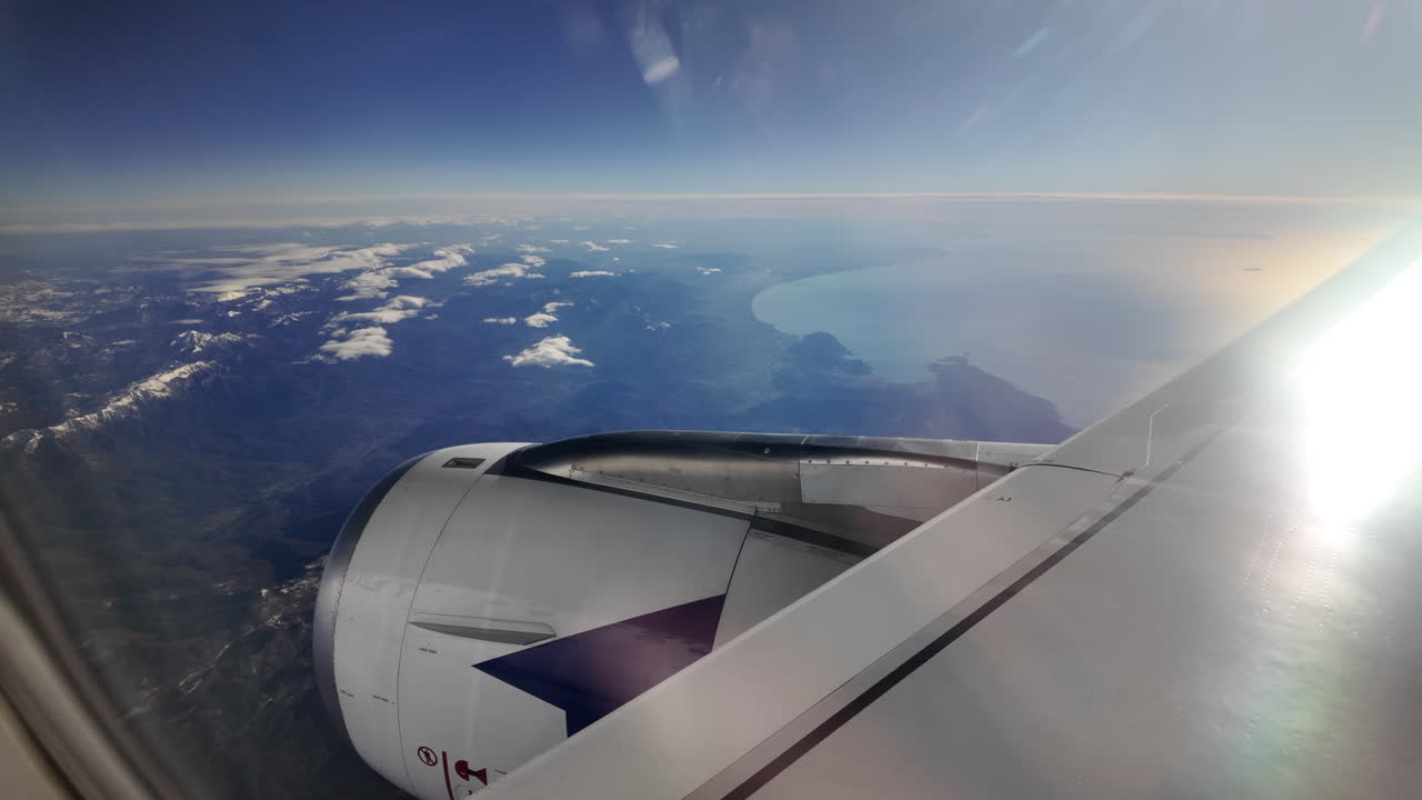 View from an airplane window of a mountain range and the sea