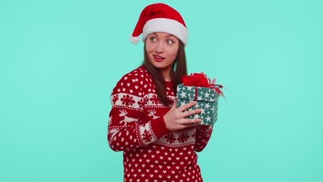 chica divertida usa suéter de año nuevo cuernos de ciervo recibido presente, interesado en lo que dentro de la caja de regalos