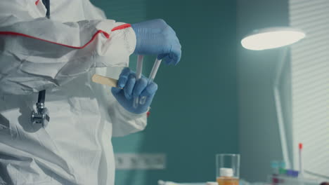 nurse taking mouth swab in protective suit gloves infectious department closeup.