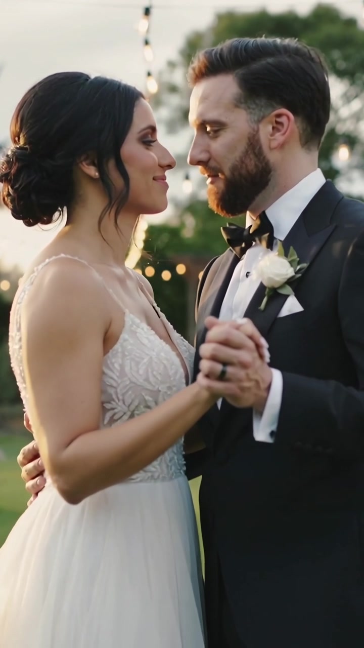 Vídeo vertical: Noivo colocando a mão e guiando a noiva dançando no gramado ao entardecer para casamento com vestido de noiva.