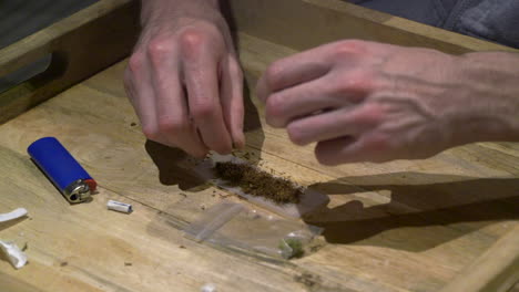 a man adding a little weed with tobacco on a rolling paper for a relaxing joint