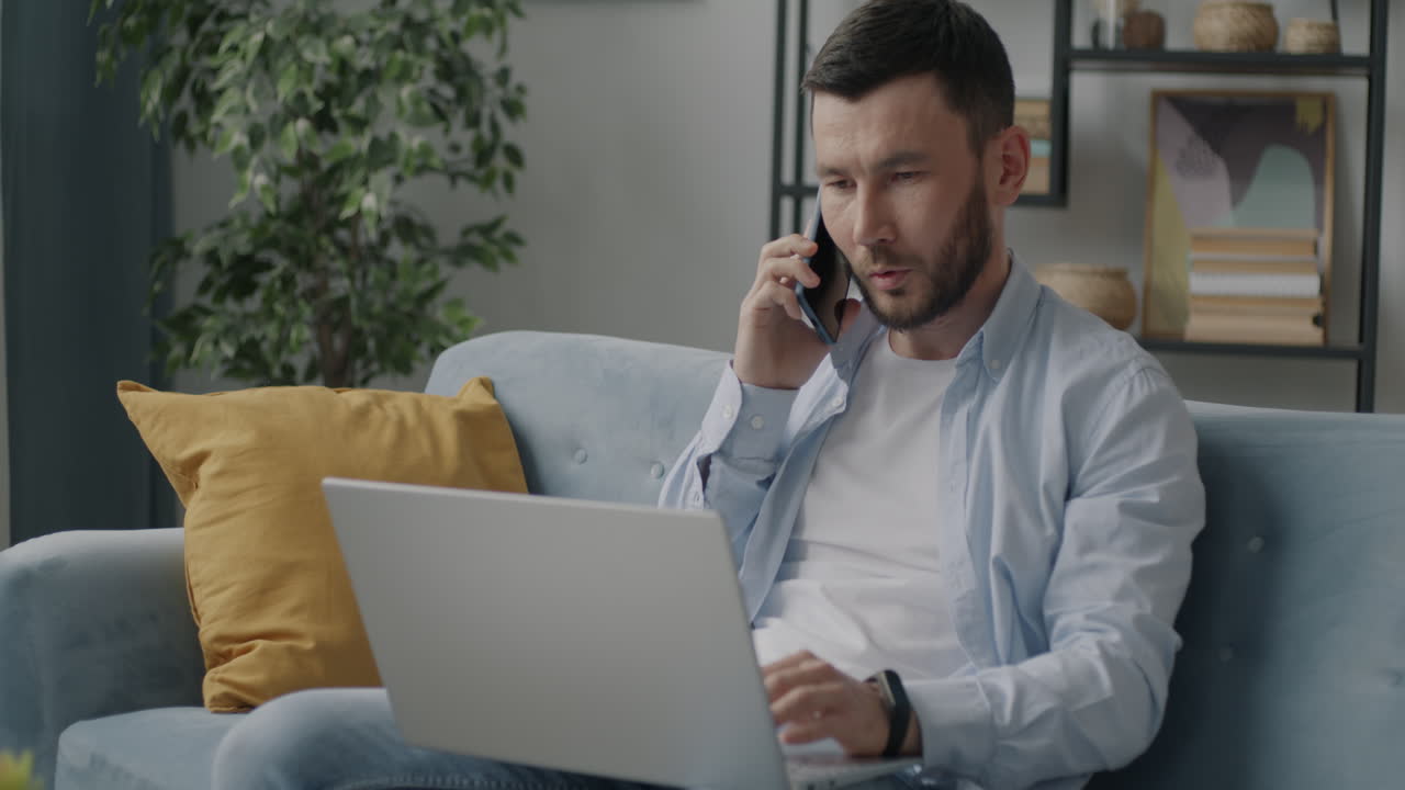 Man working from home on laptop while on phone call