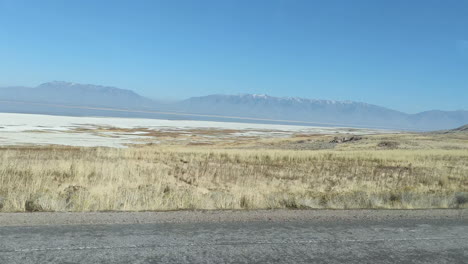 driving by the shores of the salt lake and fields of dry grass in antelope island utah