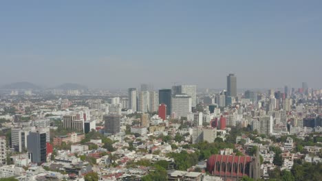 rising aerial shot of mexico city skyline on a clear day with blue skies.