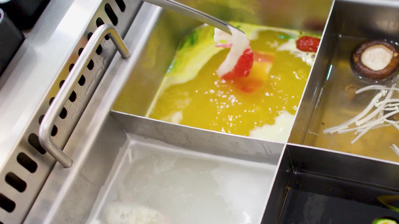 Primo piano di sottili fette di manzo immerse in brodo bollente in un ristorante