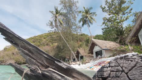 Sun-dried-wooden-tree-trunk-dividing-the-boundaries-of-the-Beach-Resort-in-Koh-Hey-,-Thailand---Wide-slide-slow-panning-shot