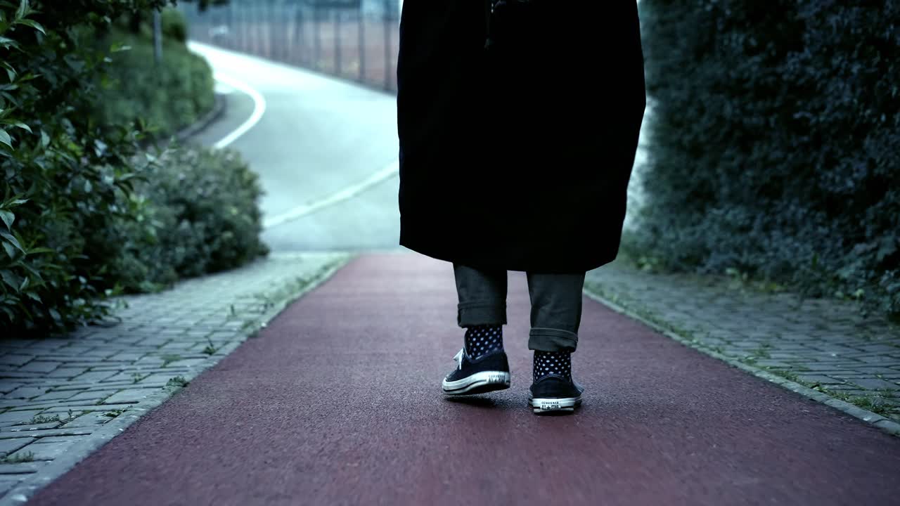 대화 신발과 긴 코트 를 입은 소녀 는 추운 가을 날 에 달리기 트랙 을  ⁇ 고 있다