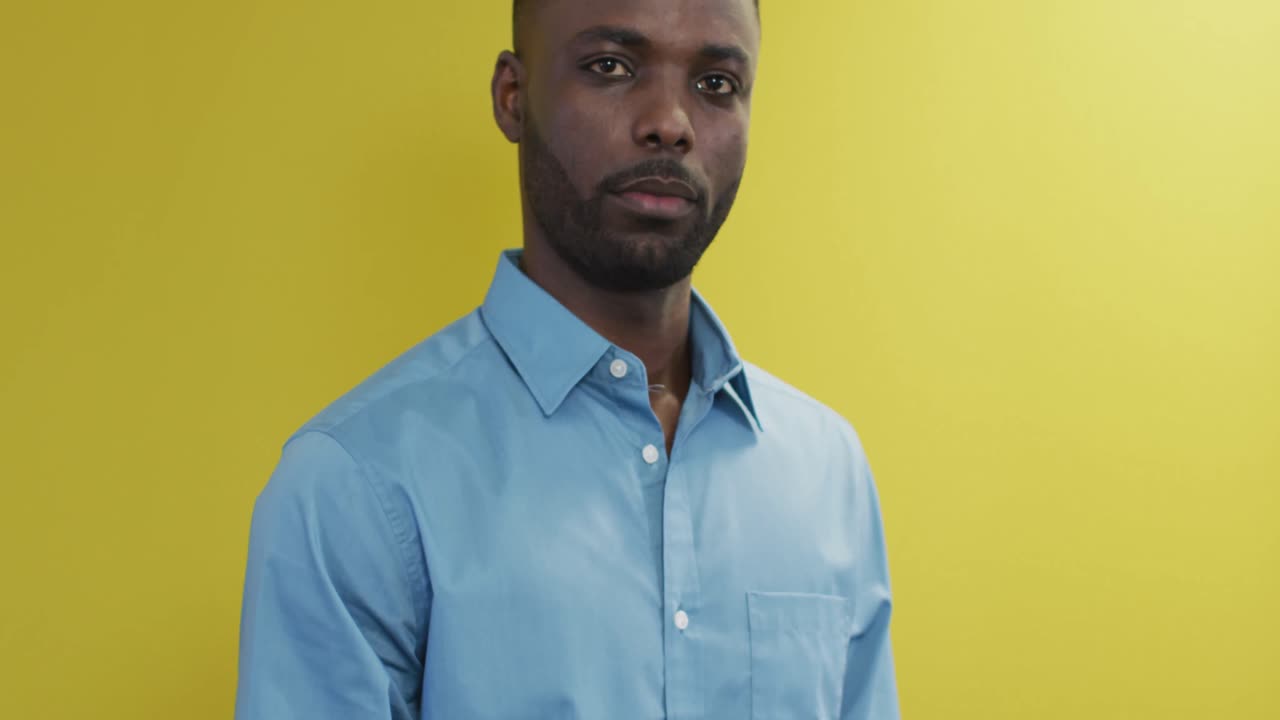 Video of smiling african american man looking at camera on yellow background