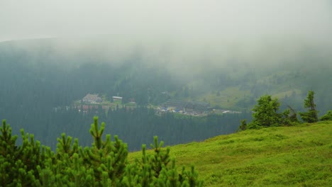 view from top of the mountain seeing hotel resort houses in the far surrounded by forest with moving clouds in front of the camera view cinematic establishing nature documentary scenery cinematic