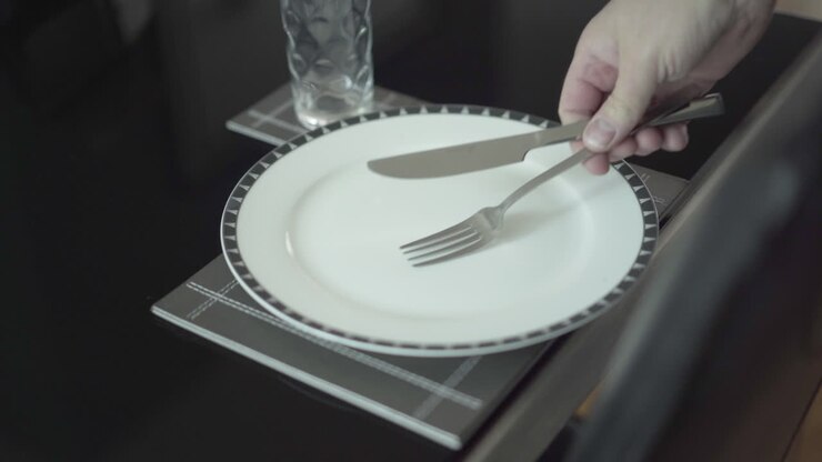 Kuvert til én ensom person, hvid tallerken, glas med kniv og gaffel