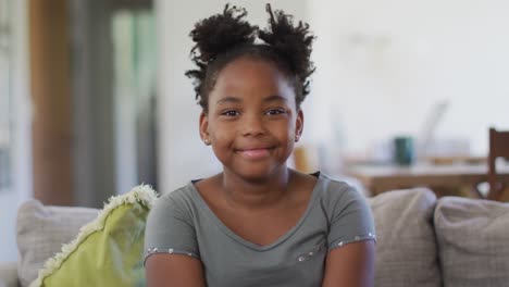 portrait of happy african american girl sitting on sofa, smiling